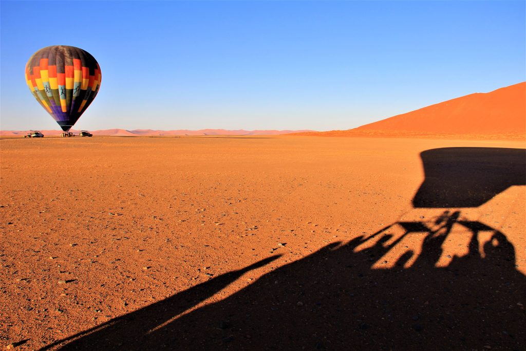 Balloon basket shadow with waving passengers, Namibia