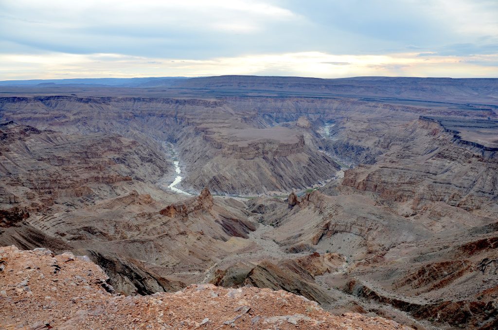 View from the rim of Fish River Canyon over layered rock terraces to the winding Fish River far below