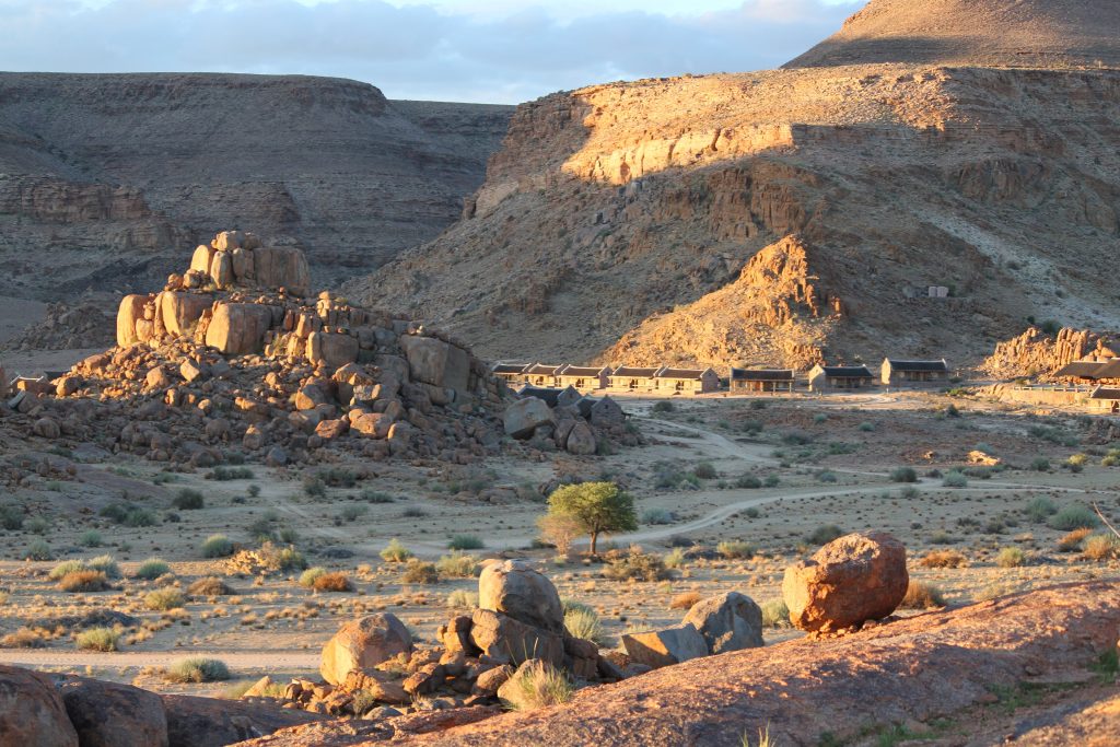 Golden evening light on a boulder-strewn koppie and the low stone chalets of Canyon Village in Gondwana Canyon Park
