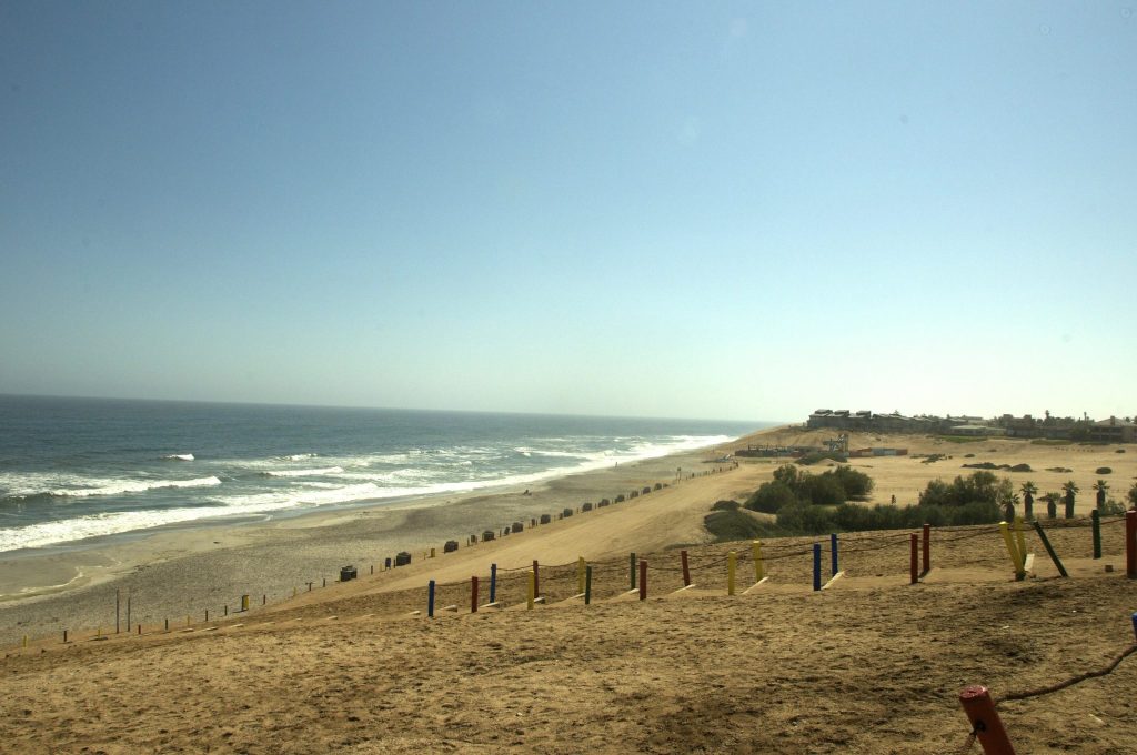 The long sandy beach at Henties Bay with Atlantic surf rolling in on the left and the low buildings of the town spread along the dune above the shore