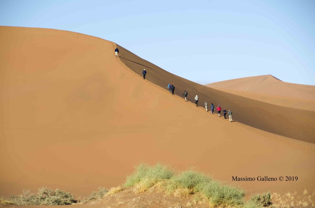 Line of tourists walking up a dune ridge, Namibia