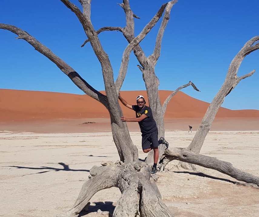 Man posing in a dead camelthorn tree, Namibia