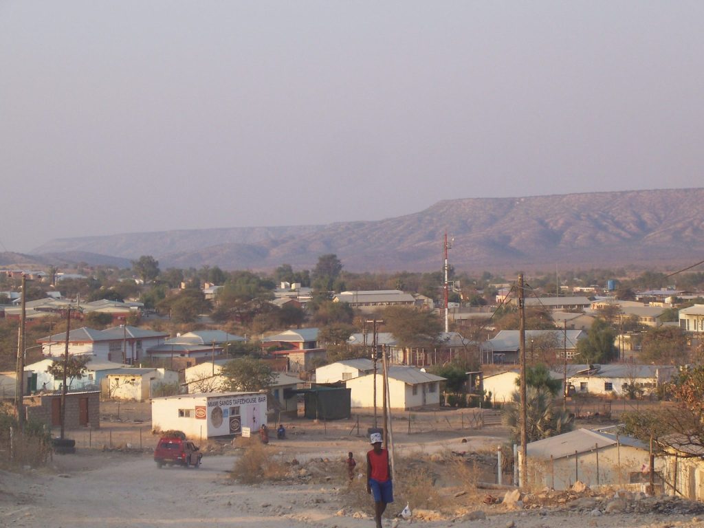 The town of Opuwo spread across a dusty valley, with tin-roofed houses, a small bar and power lines below the long flat-topped hills of the Kaokoveld