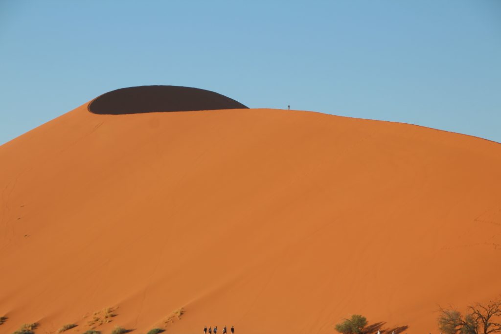 Red dune crest with lone climber silhouette, Namibia