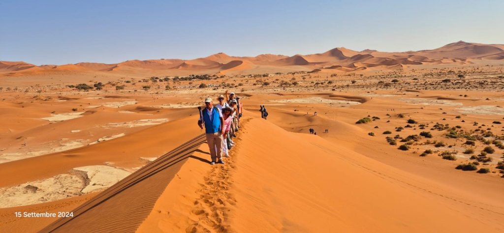 Tour group walking single file along dune ridge, Namibia