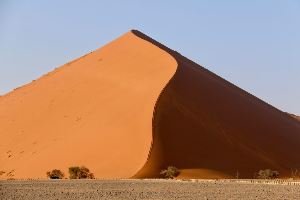 Towering red dune with knife edge crest above 4x4, Namibia