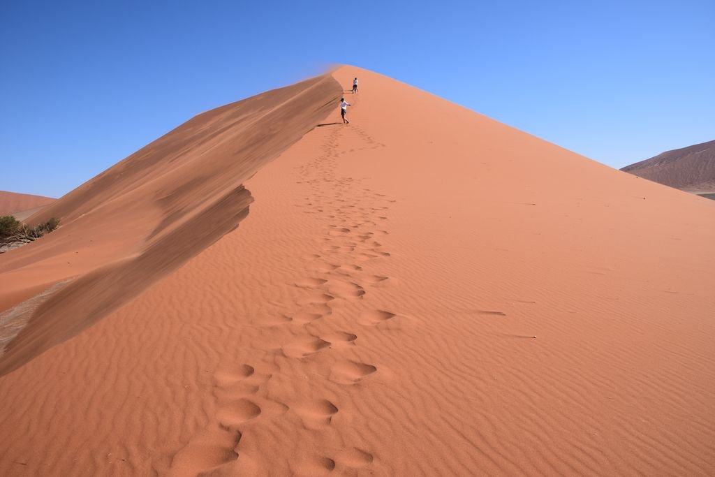 Two climbers on windblown dune crest, Namibia